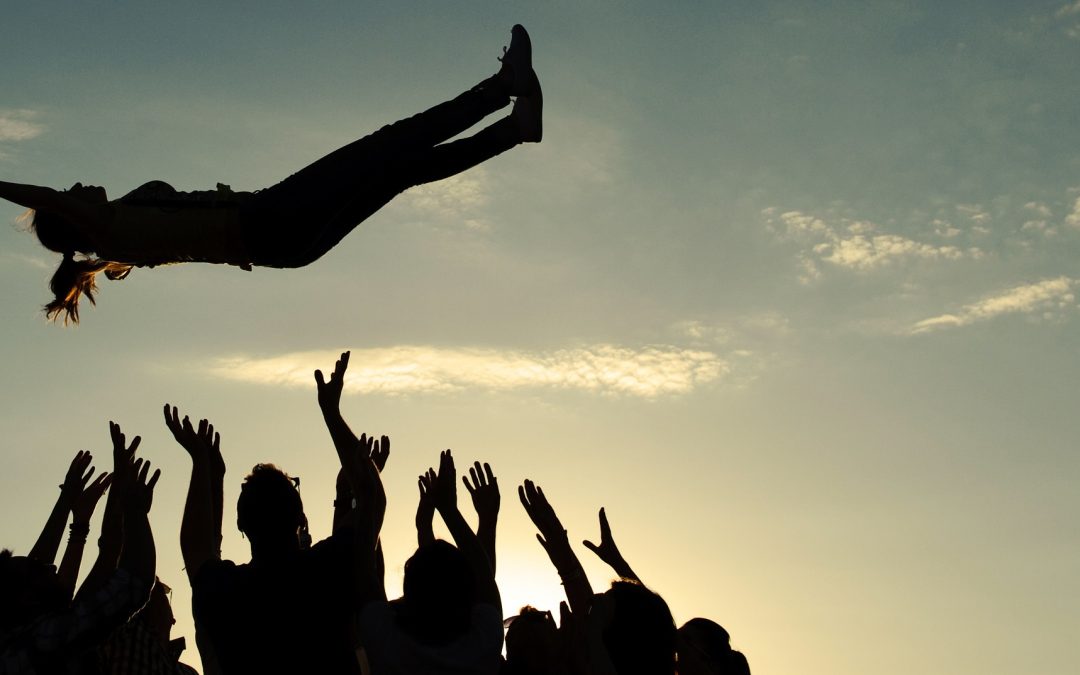 Small group of business people joining hands, low angle view.